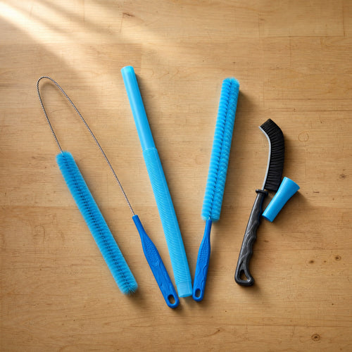 The kit laid out on a bench: two lint brushes, the flat vacuum hose, a stiff hand brush and the connector sleeve