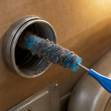 A lint brush pulled back out of the dryer duct, loaded with grey lint